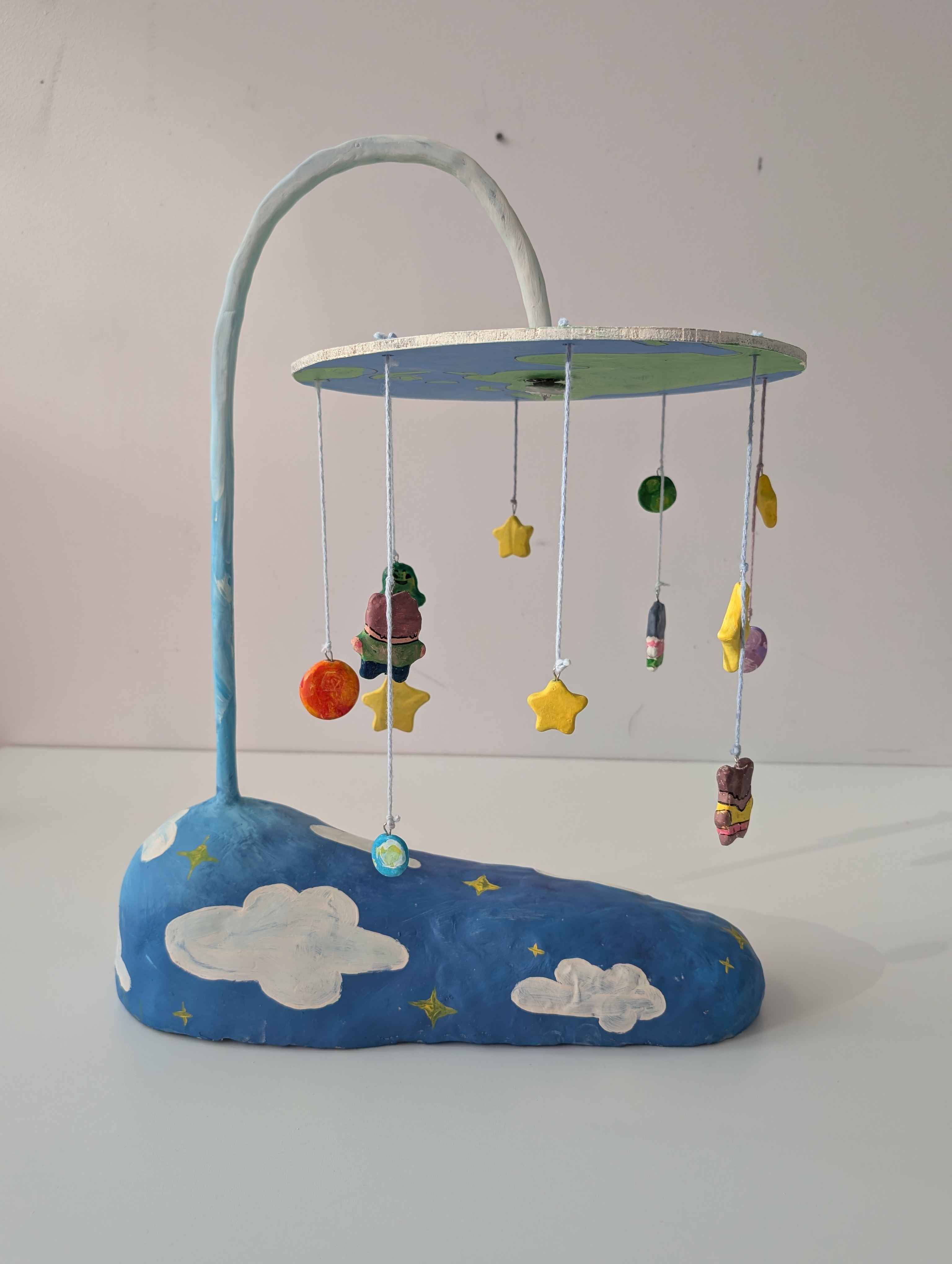 A mobile suspended like a lamp with children, stars, planets, and an alien hung