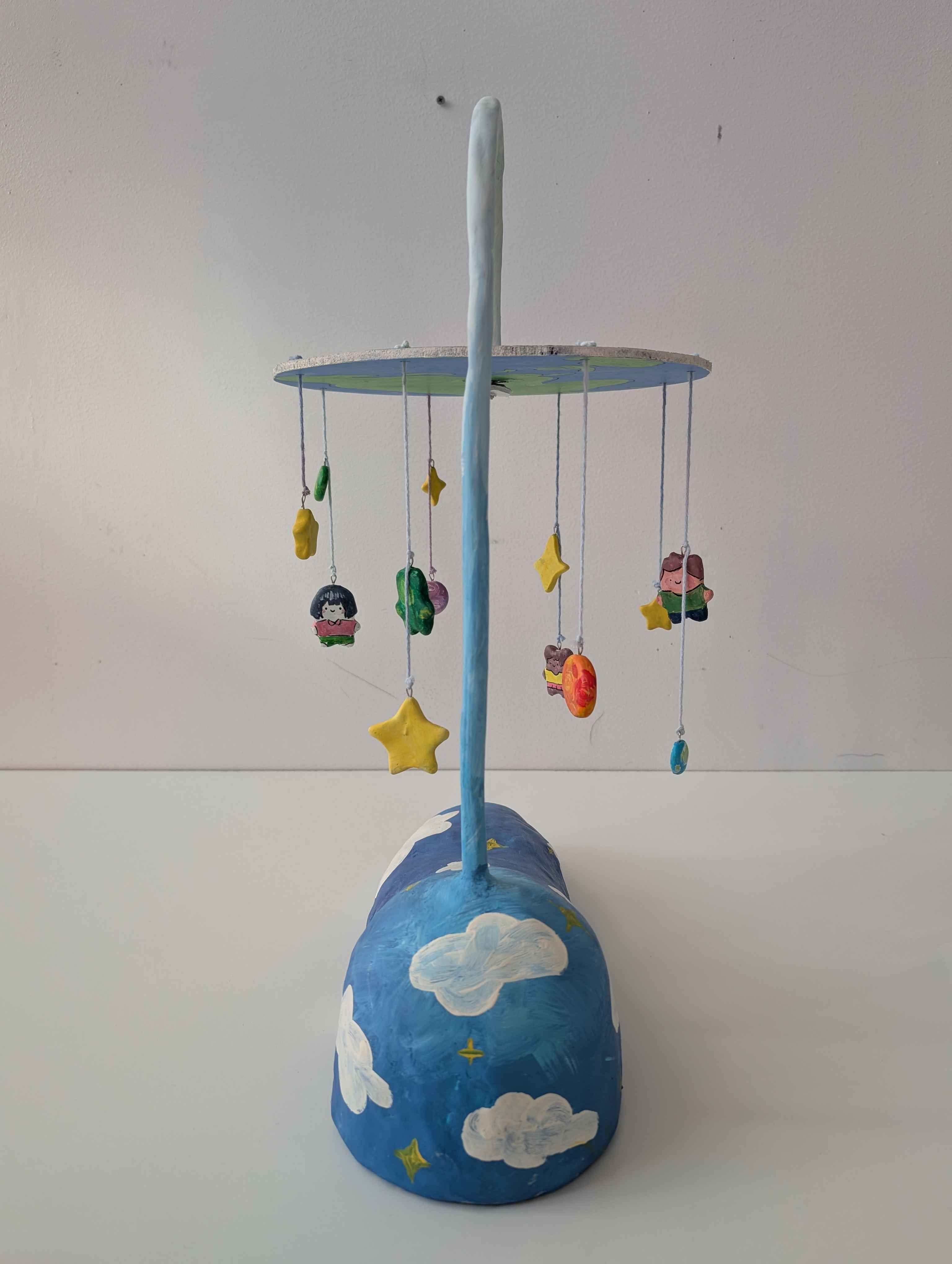 A mobile suspended like a lamp with children, stars, planets, and an alien hung