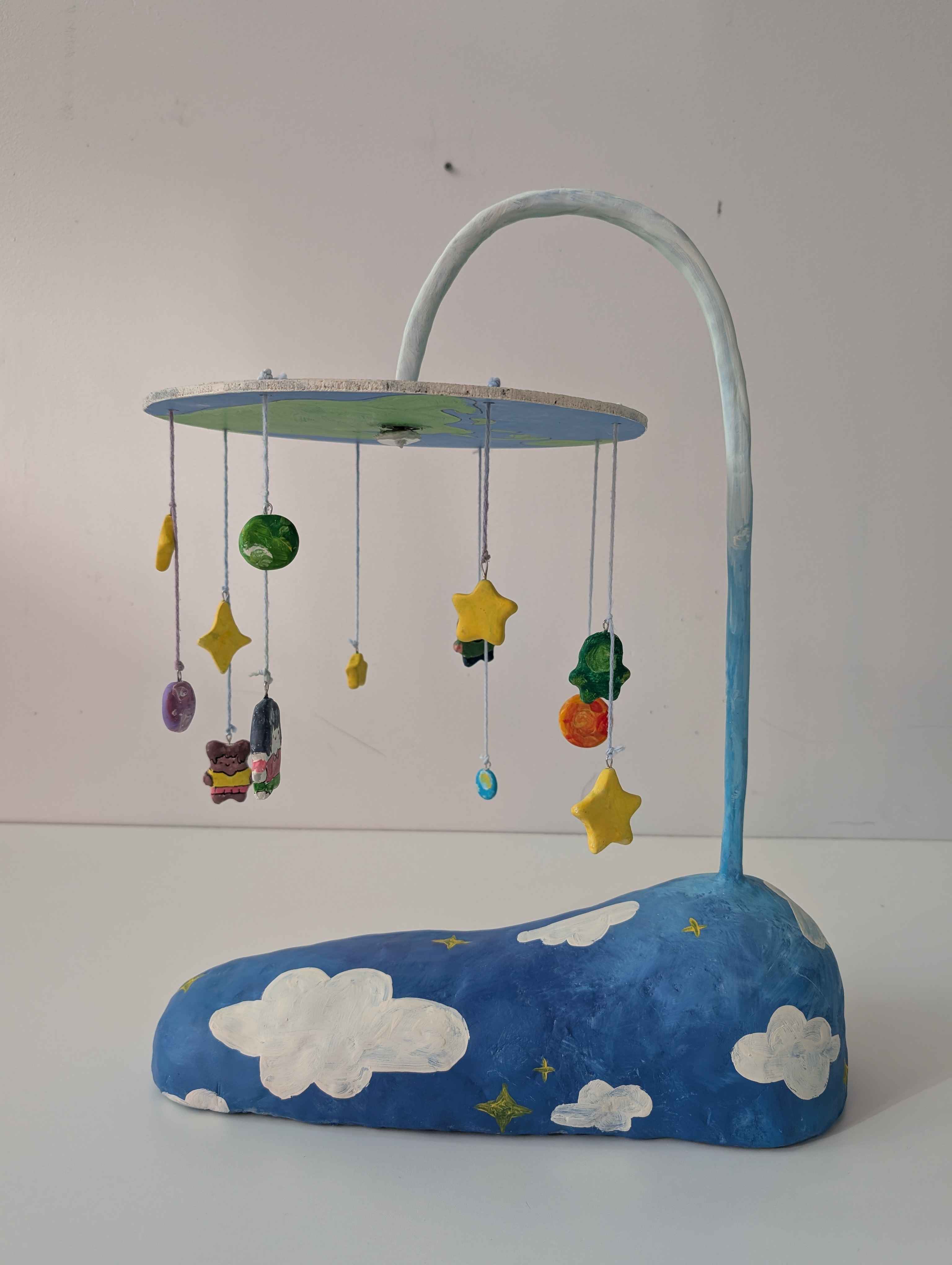 A mobile suspended like a lamp with children, stars, planets, and an alien hung
